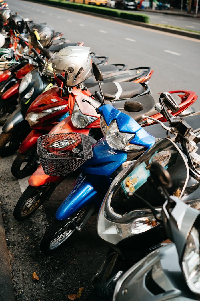 A row of colorful motor scooters parked along a city street, depicting urban transportation.